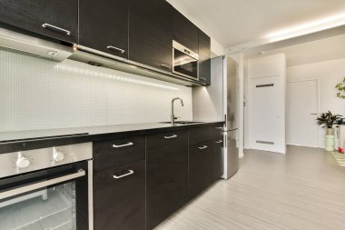 Karanlık dolaplar, paslanmaz çelik aletler ve çağdaş yaşam için mükemmel minimalist estetik içeren geniş ve şık bir mutfak..