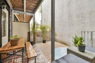 Ahşap mobilyalar, saksı bitkileri ve rahatlatıcı bir atmosfer içeren sakin bir balkon alanı. Rahatlamak ve doğanın tadını çıkarmak için mükemmel..