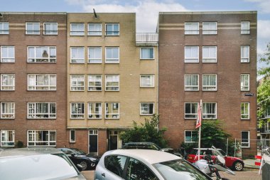 Bu resim, geniş pencereli ve çeşitli malzemelerle çağdaş mimariyi yansıtan bir çift modern apartman binası sergiliyor. Şehir yaşamını yakalar..