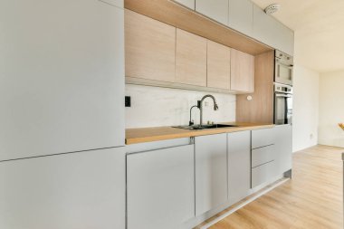 Gösterişli ve modern bir mutfak, minimalist dolap ve geniş bir düzen içeriyor, işlevsellik ve çağdaş estetiğin bir karışımını sergiliyor..