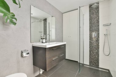Gösterişli dolaplar, zarif eşyalar ve çağdaş tasarım elementleriyle dolu geniş bir duş alanı olan modern bir banyo..