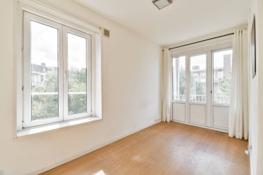 Doğal ışığı davet eden, açıklık ve sükunet hissini artıran geniş pencereli geniş ve parlak minimalist bir oda..