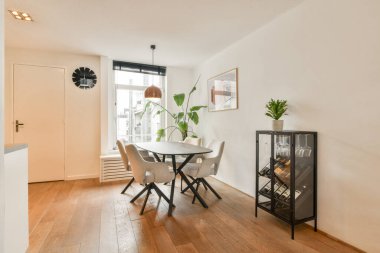 Minimalist mobilyaların, doğal ışığın ve dekoratif bitkilerin bulunduğu şık bir yemek alanı, günlük yemekler ve toplantılar için mükemmel..