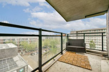 Geniş bir balkon modern bir tasarım ve parlak bir gökyüzünün altında canlı bir şehir manzarası sergiliyor. Rahatlamak ya da açık hava ortamının tadını çıkarmak için ideal..