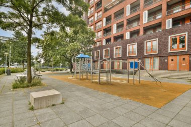 Canlı bir şehir oyun parkında modern mimari ve bereketli yeşillik, şehir ortamında mükemmel bir oyun ve rahatlama karışımı oluşturur..