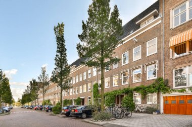 Resmedilmeye değer bir şehir caddesinde modern mimari tasarımlar sergileniyor. Her iki tarafta yeşil kaplama, ahenkli bir şehir manzarası yaratıyor..