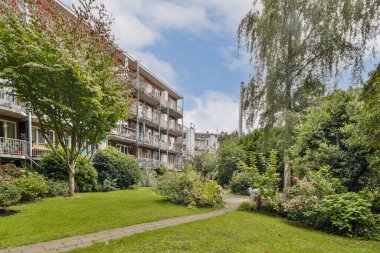 Yeşil ve modern apartmanlarla çevrili sakin bir bahçe yolu, huzurlu bir yerleşim ortamı yaratıyor..