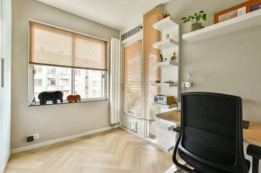 Geniş pencereli, ahşap döşemeli ve minimalist dekorlu çağdaş bir ofis. Bölge, şık mobilyalarla üretkenlik ve konfor için tasarlandı..
