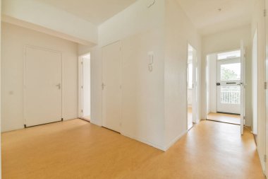 Minimalist tasarım, beyaz duvarlar ve ahşap döşeme içeren geniş ve iyi ışıklandırılmış bir iç koridor. Modern mimari tarzını sergilemek için ideal..