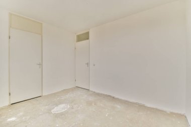 Beyaz duvarları ve beton zemini olan boş bir oda, çeşitli kullanımlar için minimalist ve temiz bir estetik ideal sağlıyor..