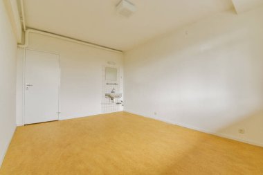 Açık renkli duvarları ve ahşap zemini olan geniş, minimalist boş bir oda, tasarım ilhamı veya emlak vitrinleri için ideal..