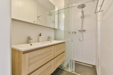 Cam bir duş, modern eşyalar ve modern dolap şiirleri olan şık bir banyo, çağdaş ev estetiği için mükemmel..