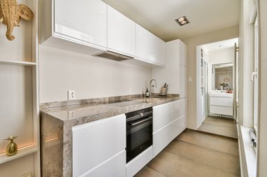 Parlak, modern bir mutfak, gösterişli beyaz dolaplar, şık bir tezgah, ve minimalist estetik için çağdaş aletler..