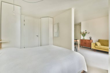 Beyaz paletli, minimalist bir dekorun sergilendiği sakin bir yatak odası, uysal bir yaşam alanı yaratmak için hafif ışıklandırma ve basit mobilyalar..