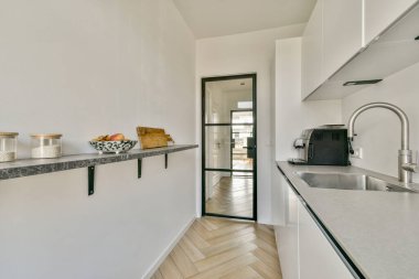 Pürüzsüz, modern bir mutfak. Temiz hatları, minimalist dekorları ve açık renk paleti var. Doğal ışık açık alanda akar ve parlak bir atmosfer yaratır..