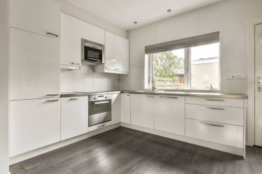 Beyaz dolaplar, paslanmaz çelik aletler ve çağdaş yaşam alanları için ideal, temiz ve şık modern bir mutfak..
