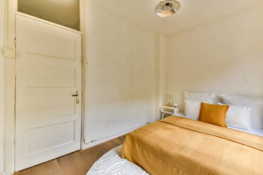 Sade bir yatak, beyaz duvarlar ve doğal aydınlatma ile sıcak renk paleti olan, rahat, minimalist bir oda..