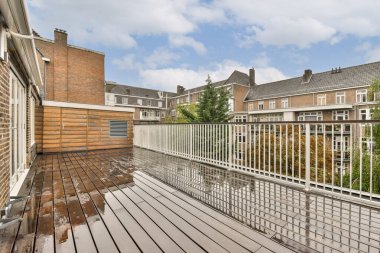 Geniş, modern bir çatı katında ahşap döşeme ve bulutlu gökyüzü altındaki kentsel binalar rahatlama ve toplanma için mükemmel..