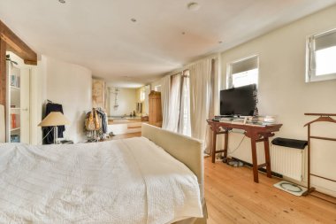 Düzenli yapılmış bir yatak, yumuşak mobilyalar ve pencerelerden süzülen bol miktarda doğal ışık içeren iç mekanlar, sakin bir atmosfer yaratıyor..