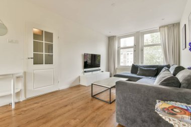 Çağdaş mobilyaların, büyük pencerelerin ve rahatlamaya ve rahatlamaya davet eden şık bir renk paletinin olduğu rahat ve modern bir oturma odası..