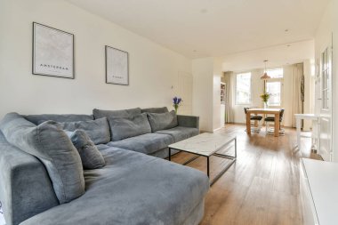 Rahat gri bir kanepe, minimalist bir kahve masası ve çiçeklerle süslenmiş bir yemek odası, rahatlama ve toplanma için mükemmel bir yer..