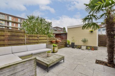 Yeşillik ve modern tasarım unsurlarıyla çevrili, rahatlama ve toplanma için mükemmel konforlu bir oturma alanı içeren çağdaş bir teras ayarı..