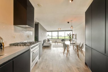 Pürüzsüz ve şık bir açık konsept mutfak. Oturma odasına sorunsuzca akıyor. Modern tasarım elementleri ve geniş doğal ışık özellikleri.