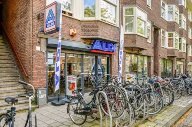 Görüntü, park halindeki bisiklet ve modern mimari ile çevrili bir Aldi süpermarket girişini gösteriyor..