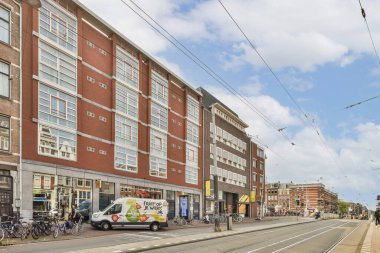 Şehir ortamında çağdaş bir mimari yapı, cam cepheler ve tramvaylı canlı bir sokak sahnesi..