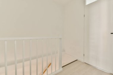 Temiz çizgiler, beyaz duvarlar ve minimalist tasarım ilkelerini vurgulayan basit bir kapının yer aldığı modern bir merdivenin parlak ve havadar bir görüntüsü..