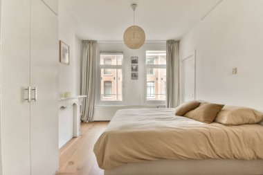 Nötr renk paleti, yumuşak yatak örtüsü, doğal ışık ve rahatlatıcı bir atmosfer yaratan minimalist dekorların yer aldığı şık ve dingin modern bir yatak odası..