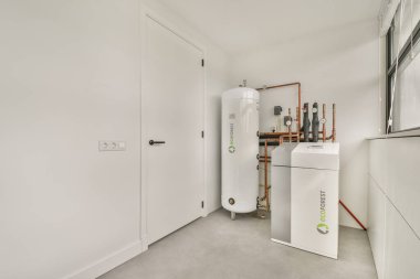 Beyaz depolama ünitesi ve minimalist bir arkaplana karşı sıkıştırılmış hava tankı da dahil olmak üzere modern ekipmanların yer aldığı gösterişli ve çağdaş bir hizmet odası..