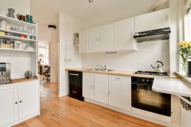 Parlak ve modern bir mutfak, gösterişli bir dolap, rahat bir düzen, ve sıcak bir yemek ortamı yaratan dekoratif unsurlar..