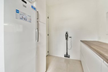 Şık, modern bir mutfak. İçinde dahili bir buzdolabı, minimalist tasarım ve zarif tezgahlar var. Işık tonları, bölgenin ferah hissini arttırır..