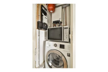 Modern bir çamaşır makinesi ve kurutma makinesinin yanı sıra gerekli aletler ve elektrik panellerinden oluşan düzenli bir çamaşır odası..