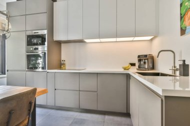 Minimalist dolaplar, paslanmaz çelik aletler ve işlevselliği ve stili vurgulayan parlak, ferah bir düzenle modern bir mutfak..