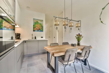 Zarif bir yemek masası, şık sandalyeler ve zevkli dekorları olan modern bir mutfak, çağdaş ortamlarda yemekler ve toplantılar için mükemmel..