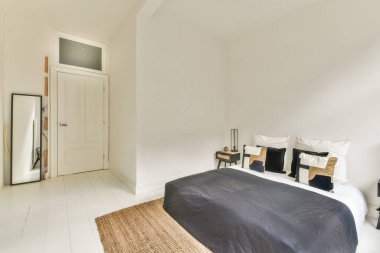 Tarafsız renkler, temiz çizgiler ve rahatlatıcı bir atmosferi teşvik eden işlevsel mobilyalarla modern bir minimalist yatak odası..