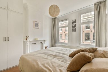 Bu modern yatak odası yumuşak ışıklandırma, rahat bir yatak odası ve geniş pencerelerle doğal ışığın boşluğu doldurarak davetkar bir atmosfer yaratıyor..