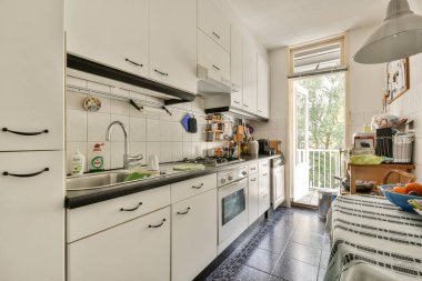 Gösterişli dolaplar, paslanmaz aletler ve geniş pencerelerden yayılan bol miktarda doğal ışık içeren modern bir mutfak..