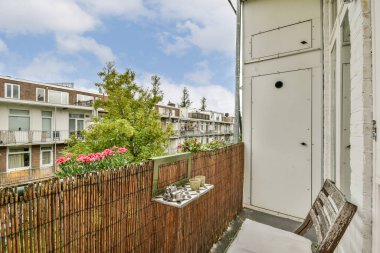 Yeşillik, renkli çiçekler ve basit bir oturma düzeninin olduğu büyüleyici bir balkon. Manzara, huzurlu ve modern bir yerleşim bölgesini ortaya koyuyor, rahatlık ve rahatlığı arttırıyor..