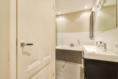 Gösterişli ve şık bir banyo. Çağdaş tasarım unsurları sergiliyor. Duş alanı, gösteriş alanı ve minimalist dekorasyon var..