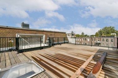 Ahşap döşemeleri, korkulukları ve çevredeki binaları ve yeşillikleri gösteren şık ve ferah bir çatı katı. Rahatlama ve toplanma için mükemmel..