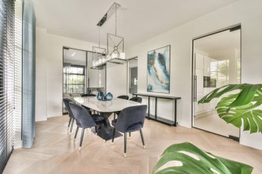 Zarif bir masa, zarif sandalyeler ve çağdaş çekiciliğini arttıran dekor unsurları olan modern bir yemek odası..