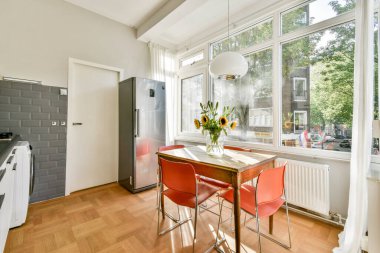 Minimalist tasarım ve çiçek süslemeleriyle vurgulanmış, güneşli bir atmosferi olan şık bir mutfak..