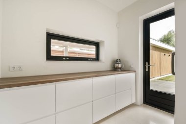 Parlak ve havadar mutfak alanı, gösterişli kabinler, ahşap tezgahlar, ve doğal ışığı davet eden büyük bir pencere, minimalist estetiği geliştiren.