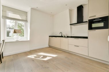 Çağdaş bir mutfak tasarımı gösterişli dolaplar, bir pencereden bol miktarda doğal ışık ve minimalist estetiği destekleyen temiz çizgiler..