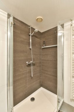 Cam duvarları ve zarif ahşap aksanları olan şık ve çağdaş duş kabini modern banyo estetiği için ideal..