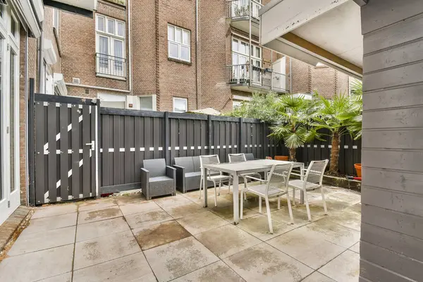 Yeşillik ve minimalist tasarım ile çevrili rahat açık hava mobilyalarının bulunduğu şık ve modern bir teras, rahatlama ve toplanma için mükemmel..