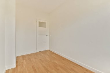 Basit bir kapı ve açık renkli duvarların yer aldığı parlak ve minimalist bir iç mekan. Ahşap zemin modern tasarıma sıcak bir dokunuş katıyor..